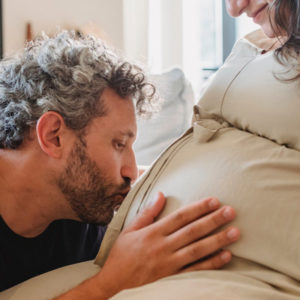 Photo of Father to be kissing Mother to be's pregnant belly